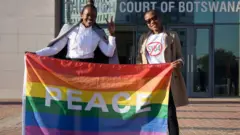 Activists pose with a rainbow flag as they celebrate outside Botswana High Court in Gaborone after the landmark ruling in June