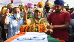 Kashmir Kaur (C) gestures after laying the wreaths of flowers on the coffin of her son and soldier Satnam Singh