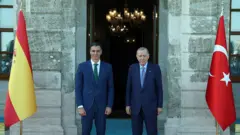 Erdoğan ve Sanchez Dolmabahçe girişi önünde kameraya bakıyor, mavi halıalar yanlarında ülkelerinin bayrakları var. 