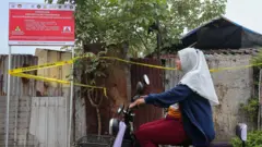 Warga menaiki sepeda listrik saat melintas di dekat plang pengawasan kerawanan bahaya radiasi.