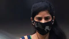 woman wearing a protective face mask walks along a street in smoggy conditions in New Delhi on November 4, 2019