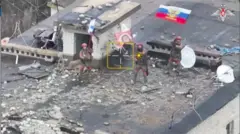 Một ảnh chụp màn hình lấy từ video cho thấy góc nhìn từ trên không cảnh các binh sĩ Nga vẫy cờ Nga trên nóc một tòa nhà, khi Nga tuyên bố đã kiểm soát thêm hai khu định cư trong khuôn khổ cuộc tấn công đang diễn ra của họ tại khu vực Donetsk ở miền đông Ukraine vào ngày 26/1/2025. 