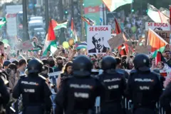 Manifestantes propalestinos con banderas y en primer plano un grupo de policías.