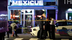 Police officers stand outside a restaurant after a shooting in Washington, DC, on July 22, 2021