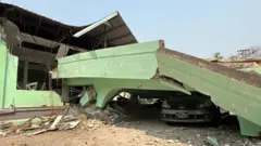Damage to a hospital showing a car crushed beneath debris