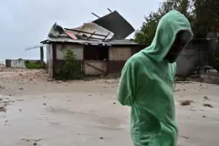 Um homem caminha perto de uma casa danificada pelos ventos preliminares do furacão Melissa em Hellshire Fishing Beach, em Portmore, Jamaica, 27 de outubro de 2025