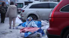 Жінка закутана в ковдри сидить біля машин на вулиці