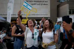 Dve žene slave u belim majicama, jedna maše izraelskom zastavom