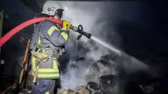 пожарный тушит дом