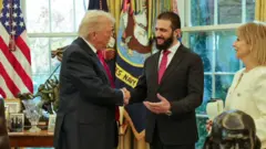 President Tramp Ahmad Ash-Sharaa bilan qo'l silkiyapti. 