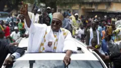 Issa Tchiroma Bakary ya na ɗaga wa magoya baya hannu daga motarsa, a lokacin da ya isa dandalin ƙaddadamar da yaƙin neman zaɓensa a birnin Yagoua, a ranar 30 ga watan Satumban 2025.