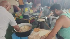 Varios miembros de la tripulación del buque Nirvana, vistos cocinando comida en el barco en una estufa improvisada en una cocina improvisada y abierta.