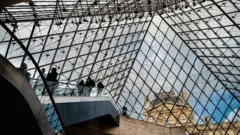 Люди на эскалаторе в Пирамиде Лувра.