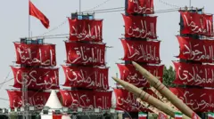 Navios com velas vermelhas e inscrições em farsi, com mísseis à frente, durante uma celebração militar no Irã