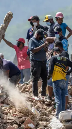 Un grupo de personas con mascarillas sobre una montaña de escombros