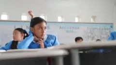 Una niña con uniforme azul en un aula de la escuela. 