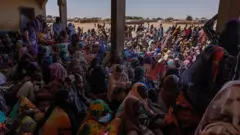 Cientos de refugiados sentados en un albergue en Chad.
