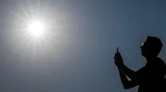 Человек с телефоном на фоне яркого солнца в безоблачном небе