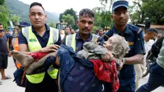 Rescatistas cargan a una anciana cubierta de barro en Nepal.