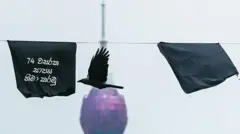 A crow flies past Black flags at the site of an ongoing protest demanding the resignation of President Gotabaya Rajapaksa over the country's crippling economic crisis in Colombo on May 6, 2022.