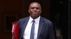 Дэвид Лэмми с красной папкой под мышкой (фото 2 сентября)