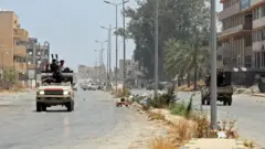 مقاتلون موالون لحكومة الوفاق الوطني الليبية المعترف بها من قبل الأمم المتحدة يركبون في شاحنة على طول طريق في منطقة قصر بن غشير جنوب العاصمة الليبية طرابلس، في 4 يونيو/حزيران 2020
