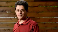 José Luis Jiménez sorri timidamente para foto, com roupa e ambiente aparentemente de verão