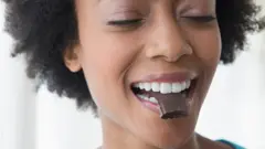 Femme avec un chocolat dans sa bouche