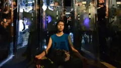 A female protester meditates in front of riot police outside the government headquarters in Hong Kong