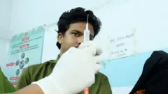 টিকা দেয়ার জন্য সিরিঞ্জ প্রস্তুত করছেন একজন স্বাস্থ্যকর্মী