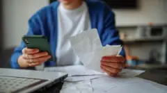 Uma pessoa segurando contas e uma calculadora.