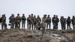 Українські солдати стоять на пагорбі з посохлою травою
