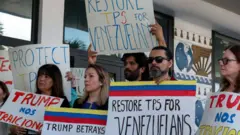Manifestantes en apoyo de los migrantes venezolanos sujetan carteles que piden la restauración del TPS y dicen "Trump nos traicionó". 