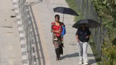 घाममा छाता ओडेर हिँड्दै महिलाहरू