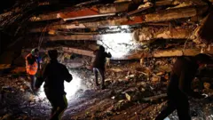 Equipes de emergência procuram vítimas no local de um prédio que desabou após um forte terremoto no distrito de Elbistan, em Kahramanmaras, sudeste da Turquia, em 7 de fevereiro de 2023