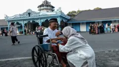Seorang perempuan mencium tangan orang tuanya seusai melaksanakan salat Idulfitri 1444 H di halaman Keraton Kasunanan Surakarta Hadiningrat Solo, Jawa Tengah, Jumat (21/04). Panitia setempat menggelar dua kali pelaksanaan salat Idulfitri 1444 H yaitu pada Jumat (21/04) dan Sabtu (22/04). 