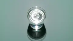 Mavi bir ekranın önünde bir bardak su