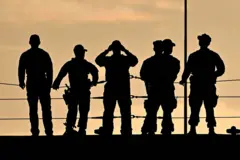 Siluetas de seis militares a contraluz en la cubierta de un barco de guerra estadounidense.