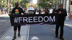 رجلان أمريكيان من أصل أفريقي يشاركان في مسيرة جونتينث ويحملان معاً لافتة من القماش كتب عليها freedom# (هاشتاج حرية)