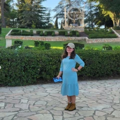 Mulher de vestido azul, com parque ao fundo