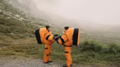 Duas pessoas com trajes laranja de astronauta nos Alpes suíços