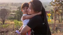 Burmese national Moe Sandar Myint hugs one of her three children, who live with her and her husband in Thailand after a harrowing escape from Myanmar