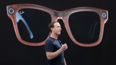 Mark Zuckerberg, CEO de Meta, en un escenario describiendo las Ray-Ban de Meta, de las cuales se muestra una gran imagen detrás de él.