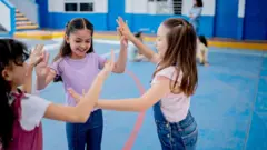 Meninas brincando dentro de um ginásio.