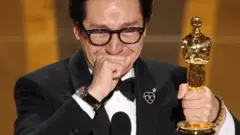 Ator Ke Huy Quan chorando com Oscar na mão