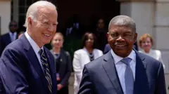 Joe Biden for di left dey smile as e shake hands with Joao Lourenco as dem meet for Luanda.