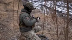 Ukraiński żołnierz przygotowuje satelitarny system internetowy Starlink na na linii frontu