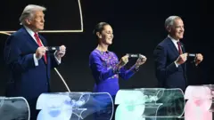 US President Donald Trump, Mexican President Claudia Sheinbaum and Canadian Prime Minister Mark Carney hold up tags bearing the names of their respective countries during the Fifa World Cup draw