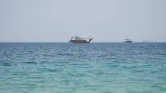 3 سفن ترى من بعيد، والموج هادئ. الصورة التقطت نهاراً.