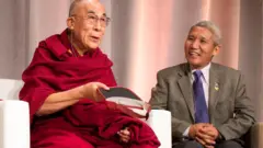 Thupten Jinpa sentado ao lado do Dalai Lama